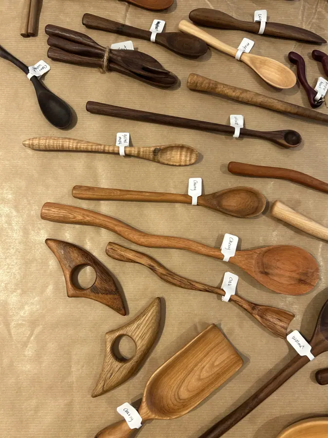 cazos y espátulas de madera tallados a mano, dispuestos sobre un banco