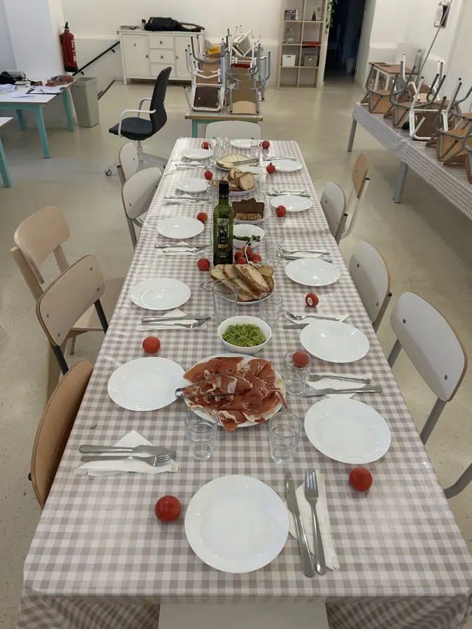 una mesa larga puesta con mantel y platos antes de una comida