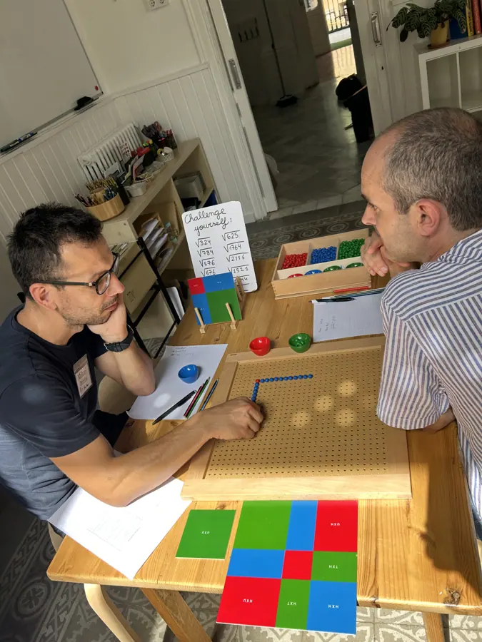 dos participantes conversando sobre una mesa cubierta de materiales