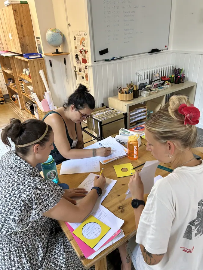 cuatro participantes trabajando juntas con materiales en una mesa