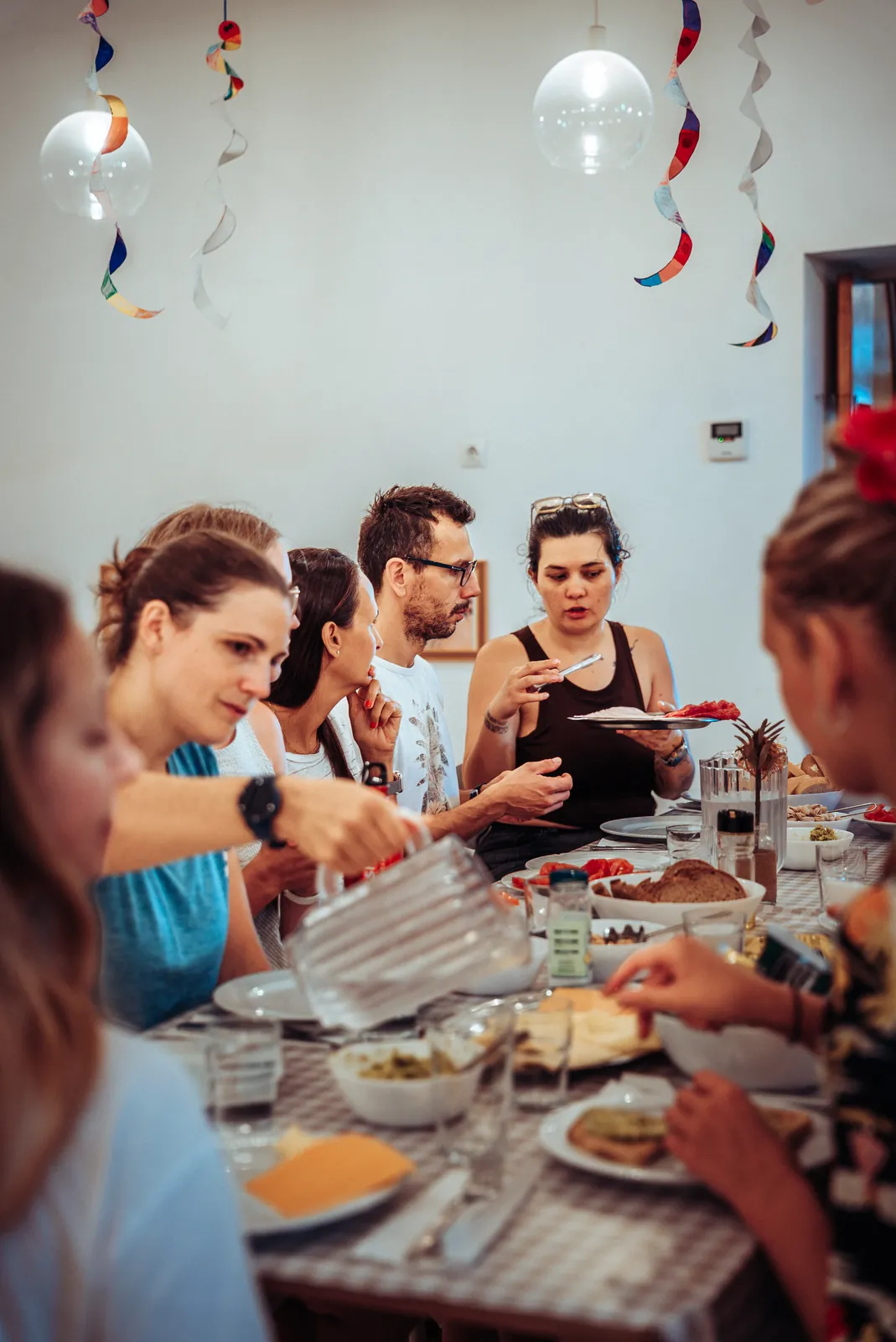 the cohort sharing a meal beneath paper decorations