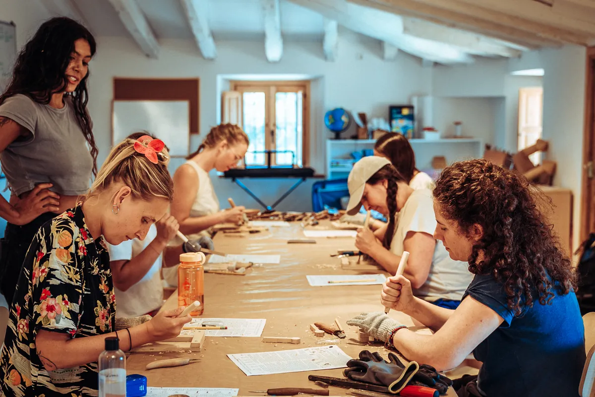 participants carving spoons together at a long workshop table